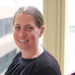 A woman with mecfs smiling in front of a window.