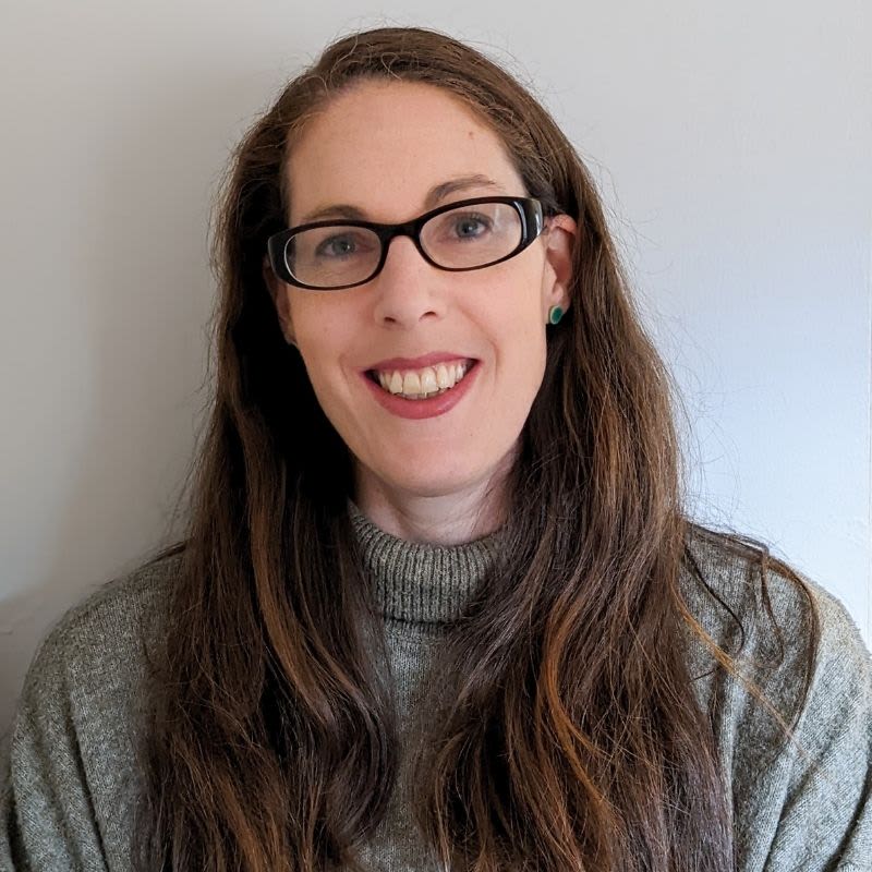 A woman with mecfs wearing glasses and a sweater.