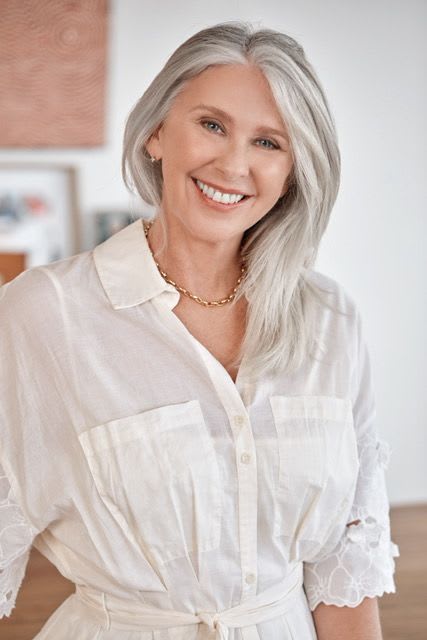 A woman with ME/CFS smiling in a white shirt.